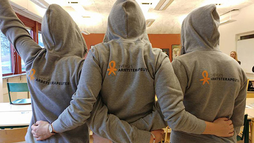 Tre studenter bakifrån i luvtröjor med förbundets logotyp