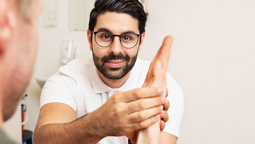 Egenföretagaren Aras Hussein undersöker en patients hand.