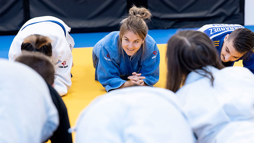 Emelie Pernheim på judomattan med elever framför sig.